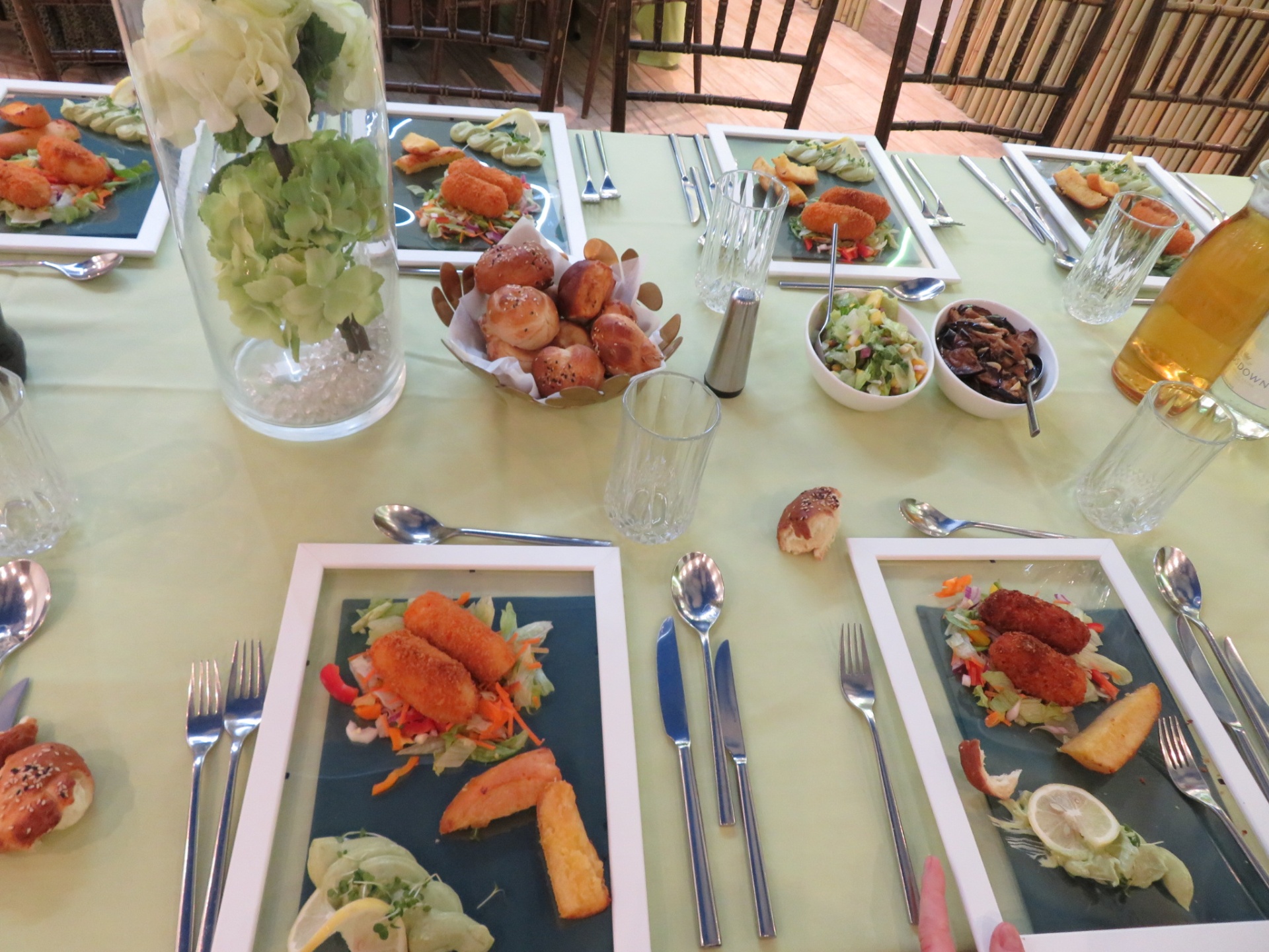 A long table set with plated meals and fresh bread rolls