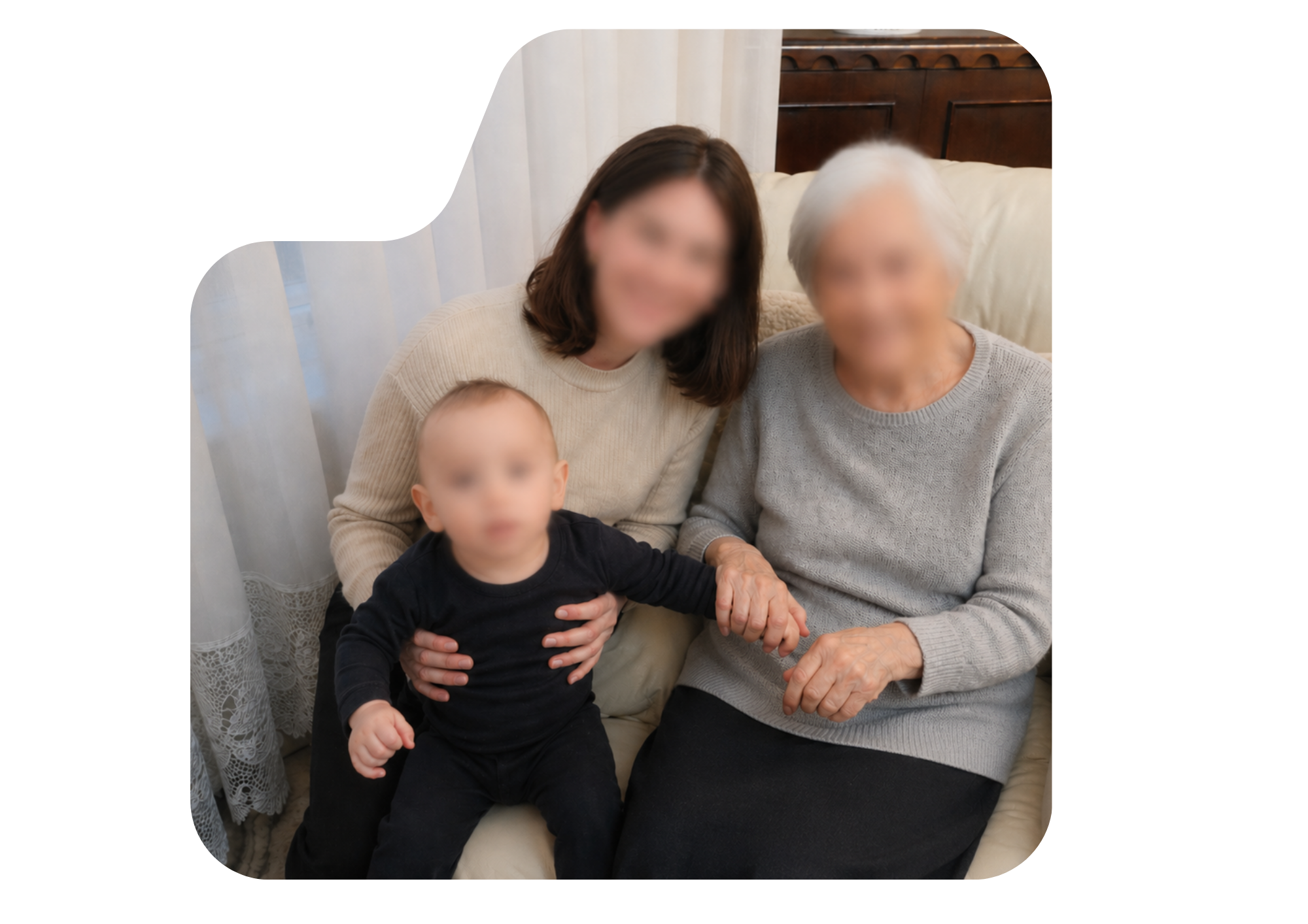 A mother, grandmother and young child sitting together on a sofa.