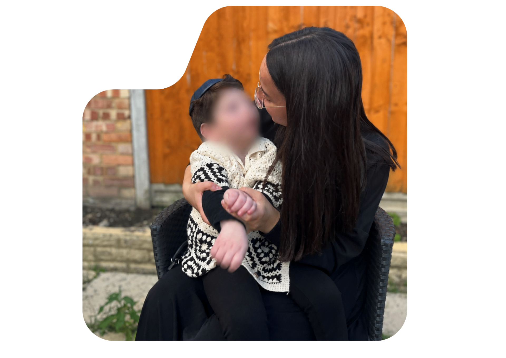 A woman seated with a child on her lap, looking at them with care and attention.