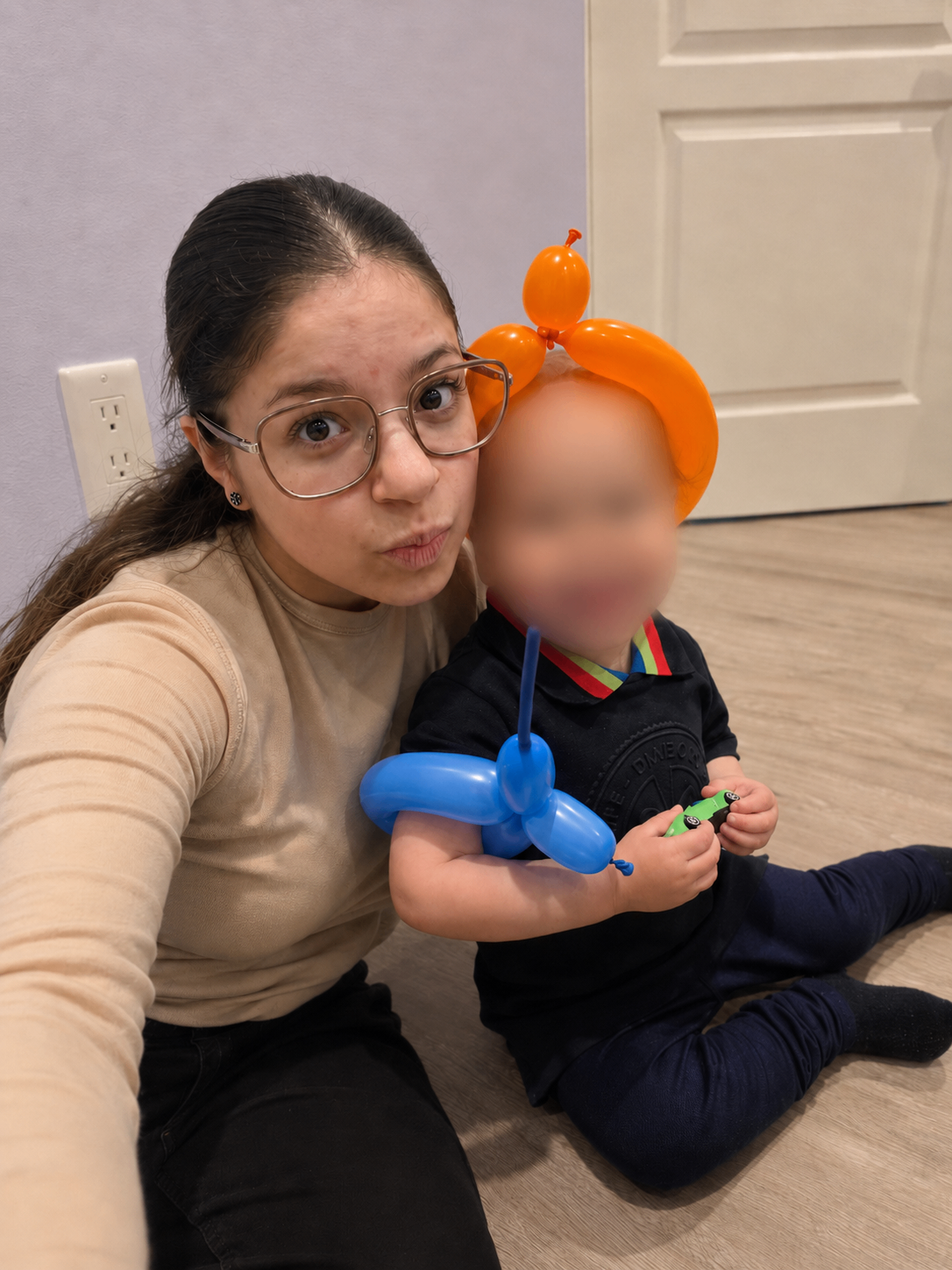 A carer with a young child holding balloon animals